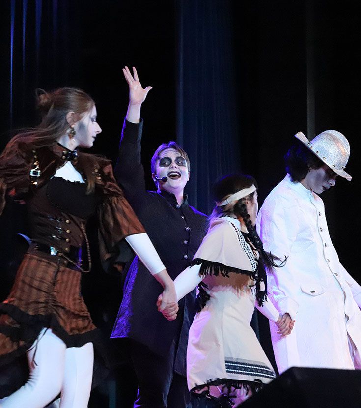 St. Thomas More students performing in theatrical costumes on stage