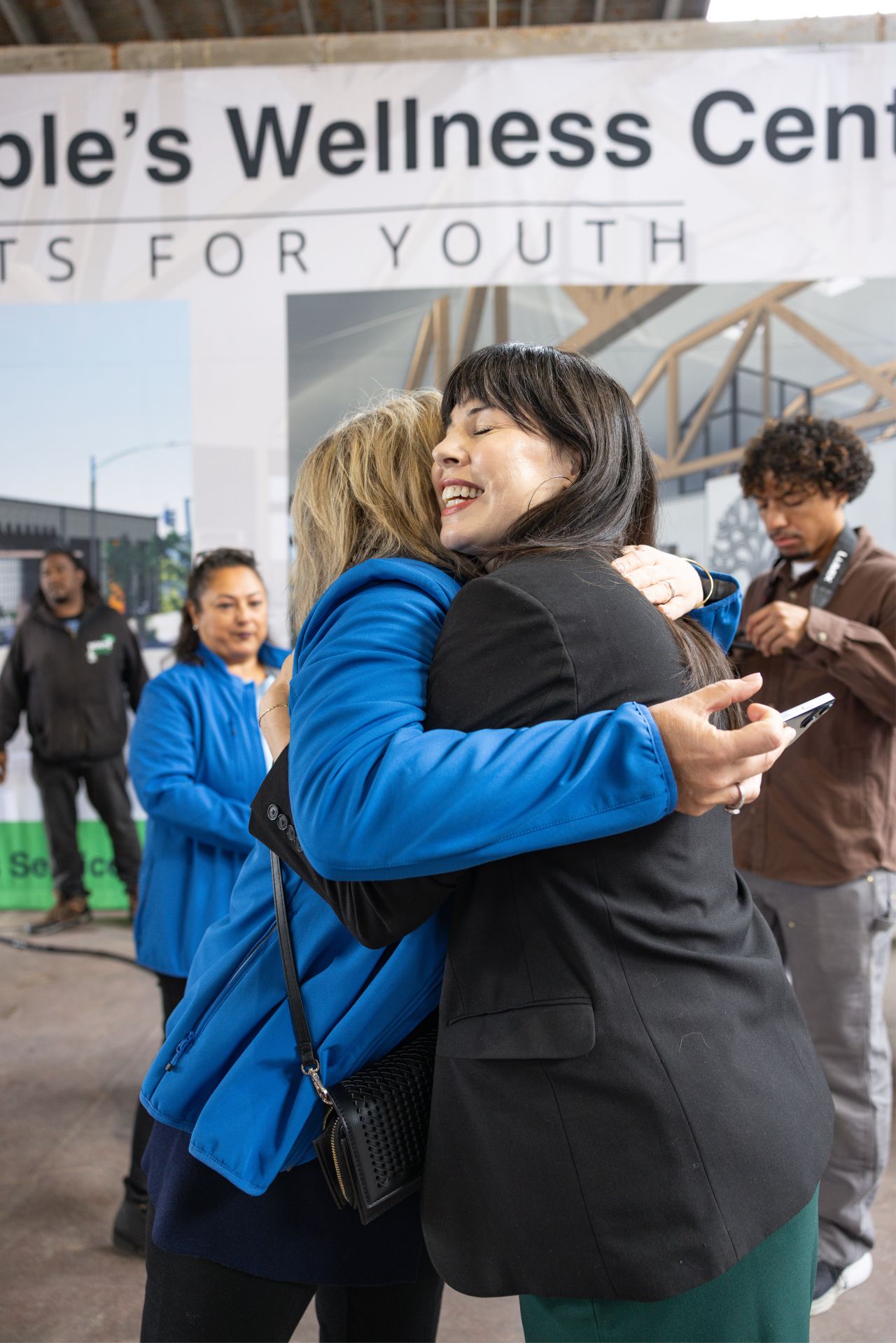 Two supporters embracing at the Roots for Youth groundbreaking celebration